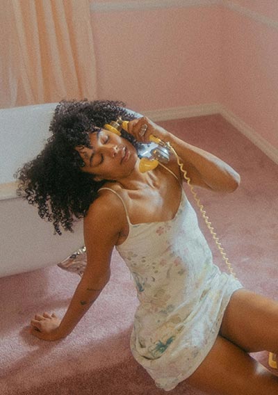 Beautiful woman sitting on the floor and talking on a retro phone.